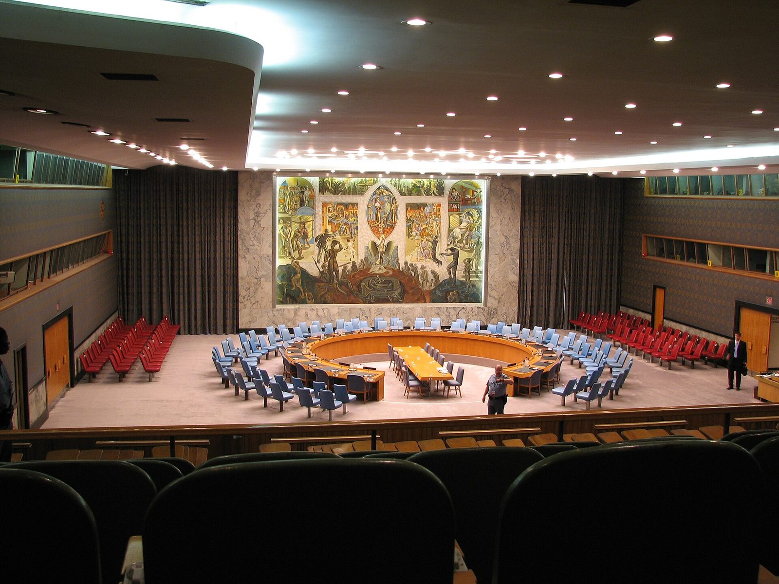 Empty circular council chamber, round table, large mural on wall