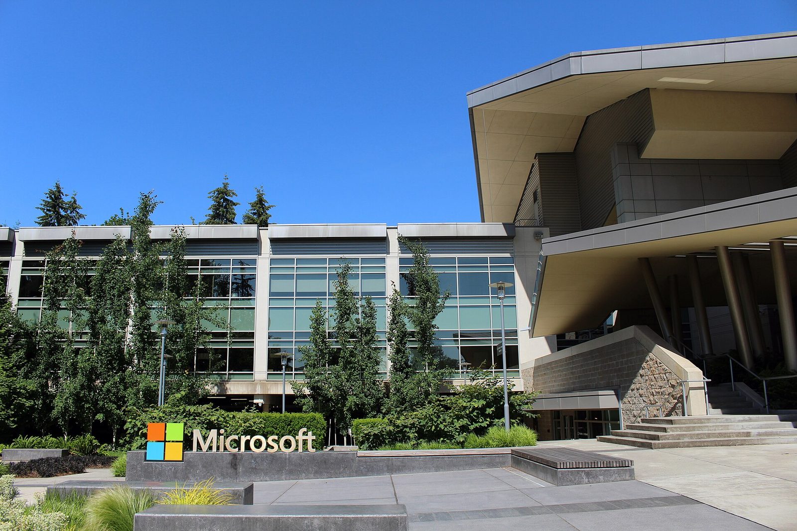 Microsoft sign in front of a glass office building, clear blue sky
