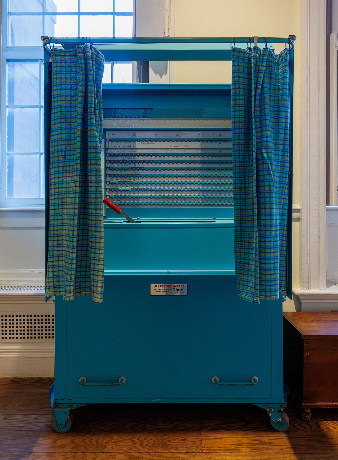 Blue enclosed voting booth with curtains inside a historic building