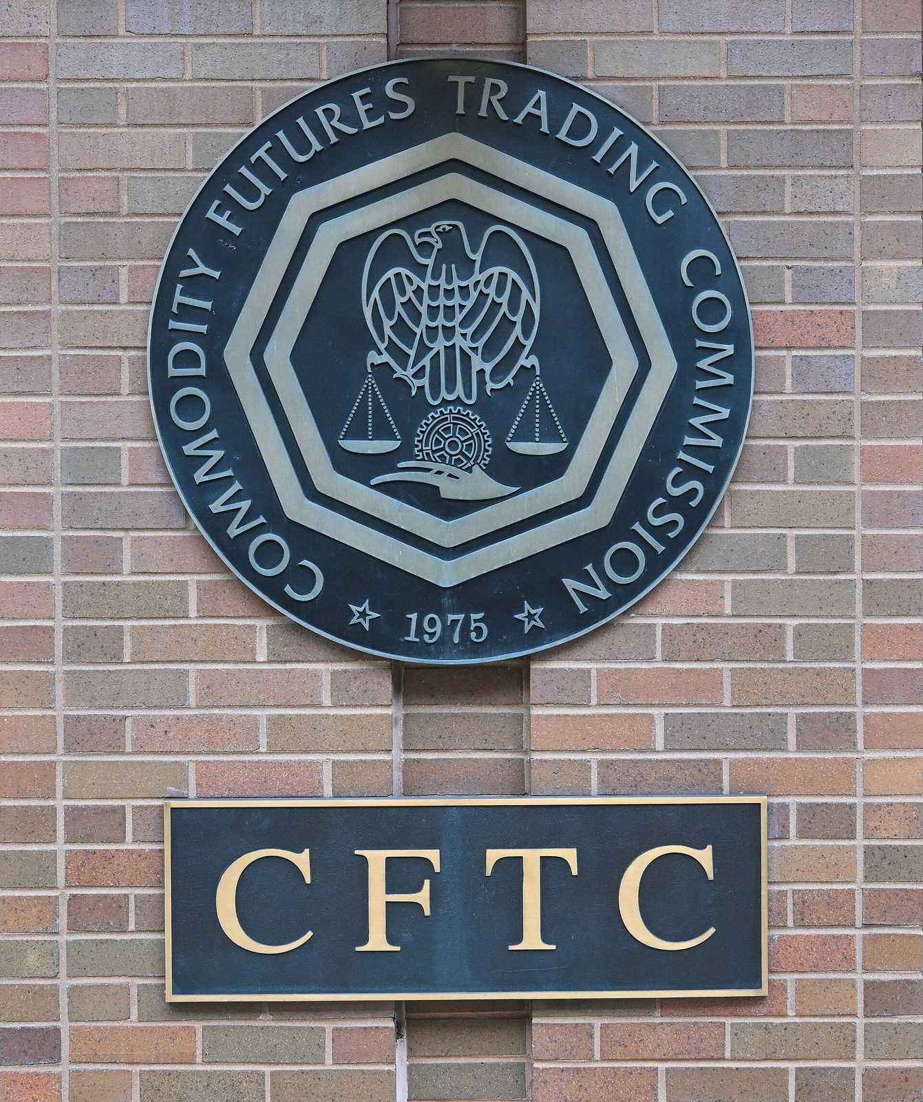 Circular CFTC seal plaque mounted on a brick wall