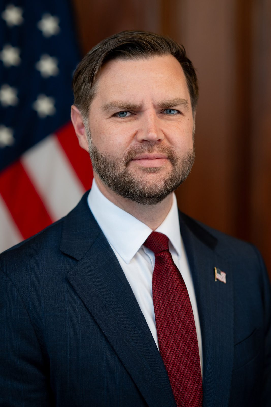 Official portrait of a man in suit with US flag in background