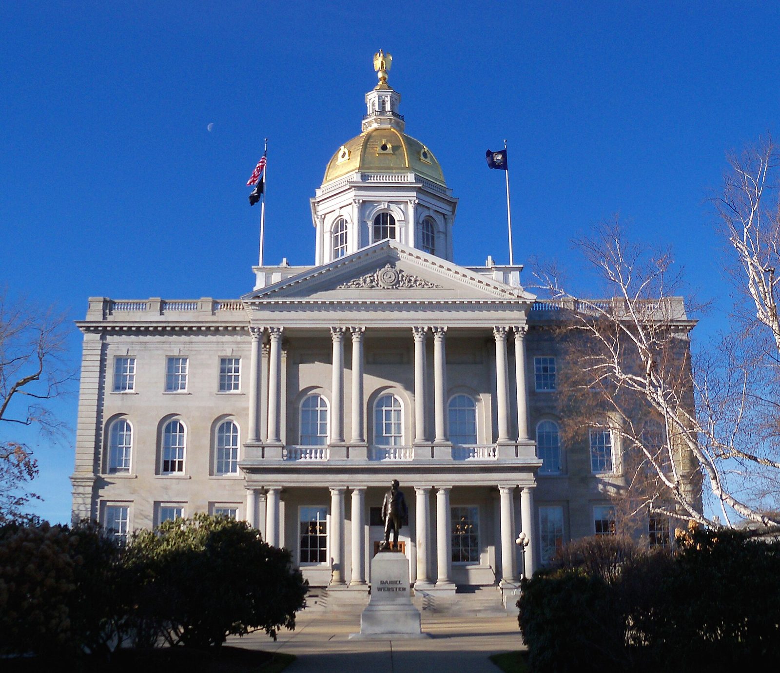 Stone building with gold-domed cupola, columns and statue in front, New Hampshire