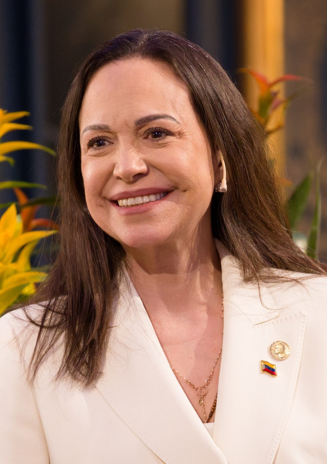 close portrait of a smiling woman wearing a white jacket, lapel pin