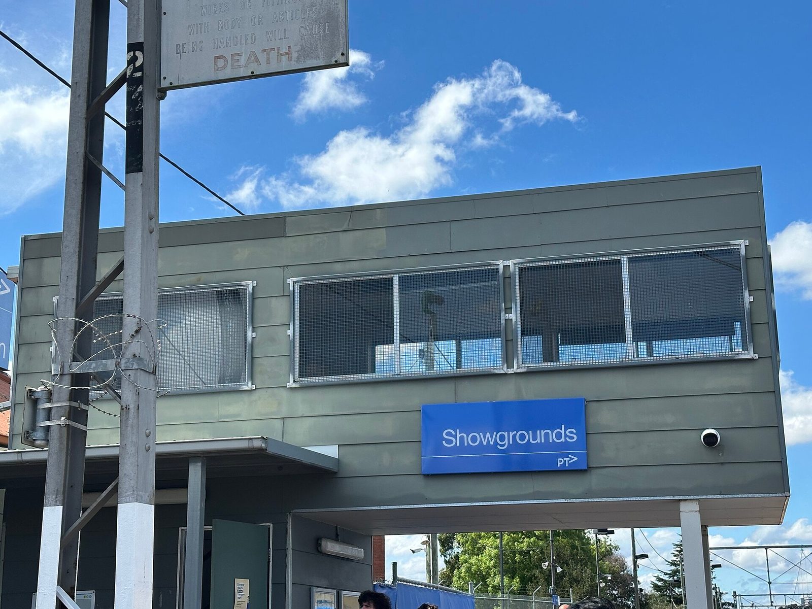 station building with blue 'Showgrounds' sign under sky, Melbourne Showgrounds