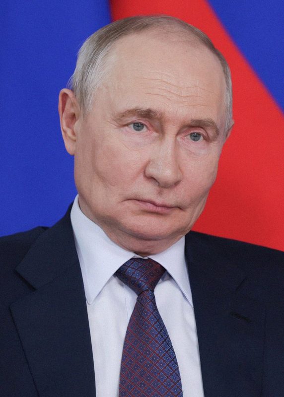 Close-up portrait of a man in a suit, blue and red flag