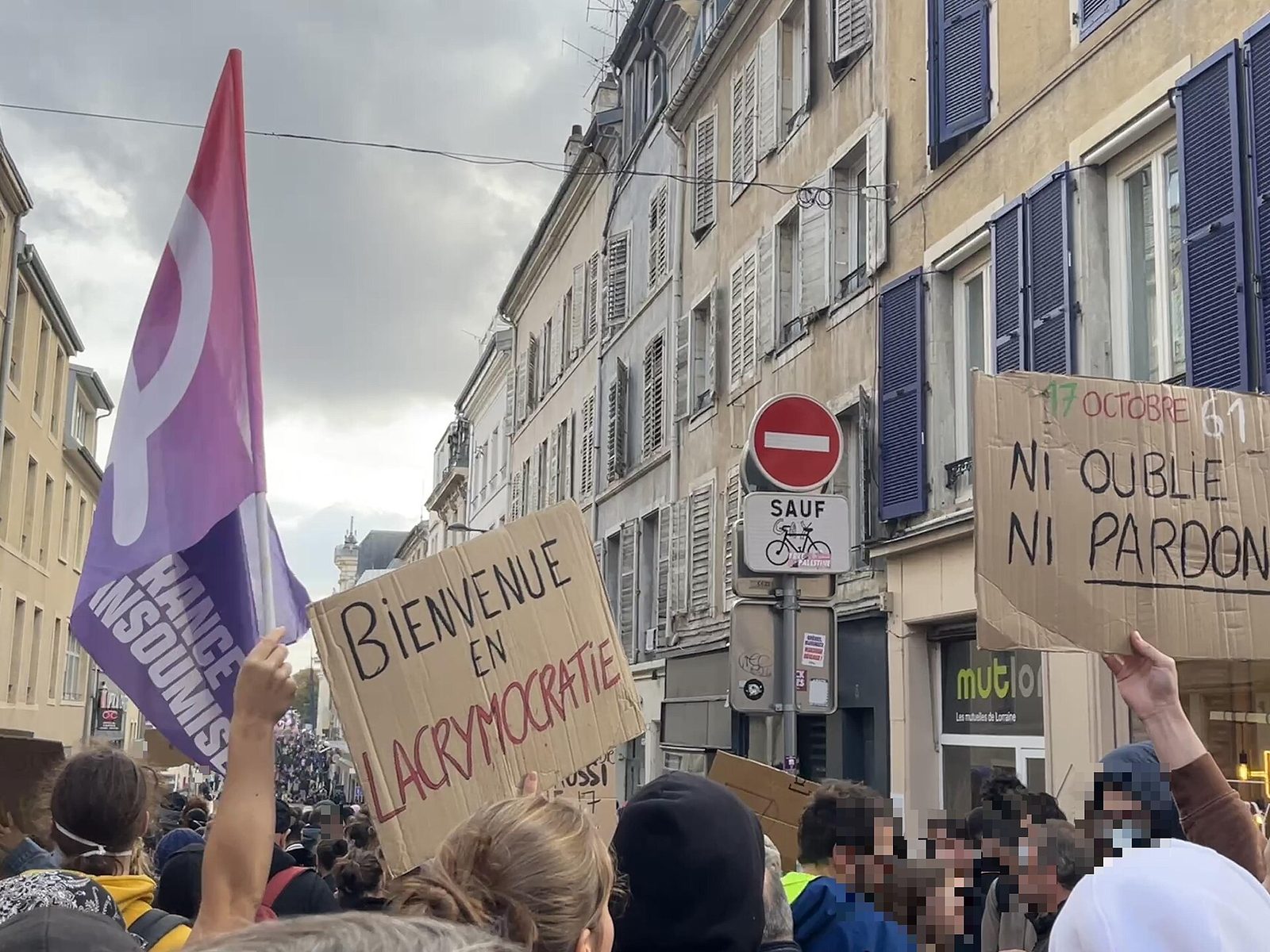 Crowd holding cardboard placards and a purple flag on street
