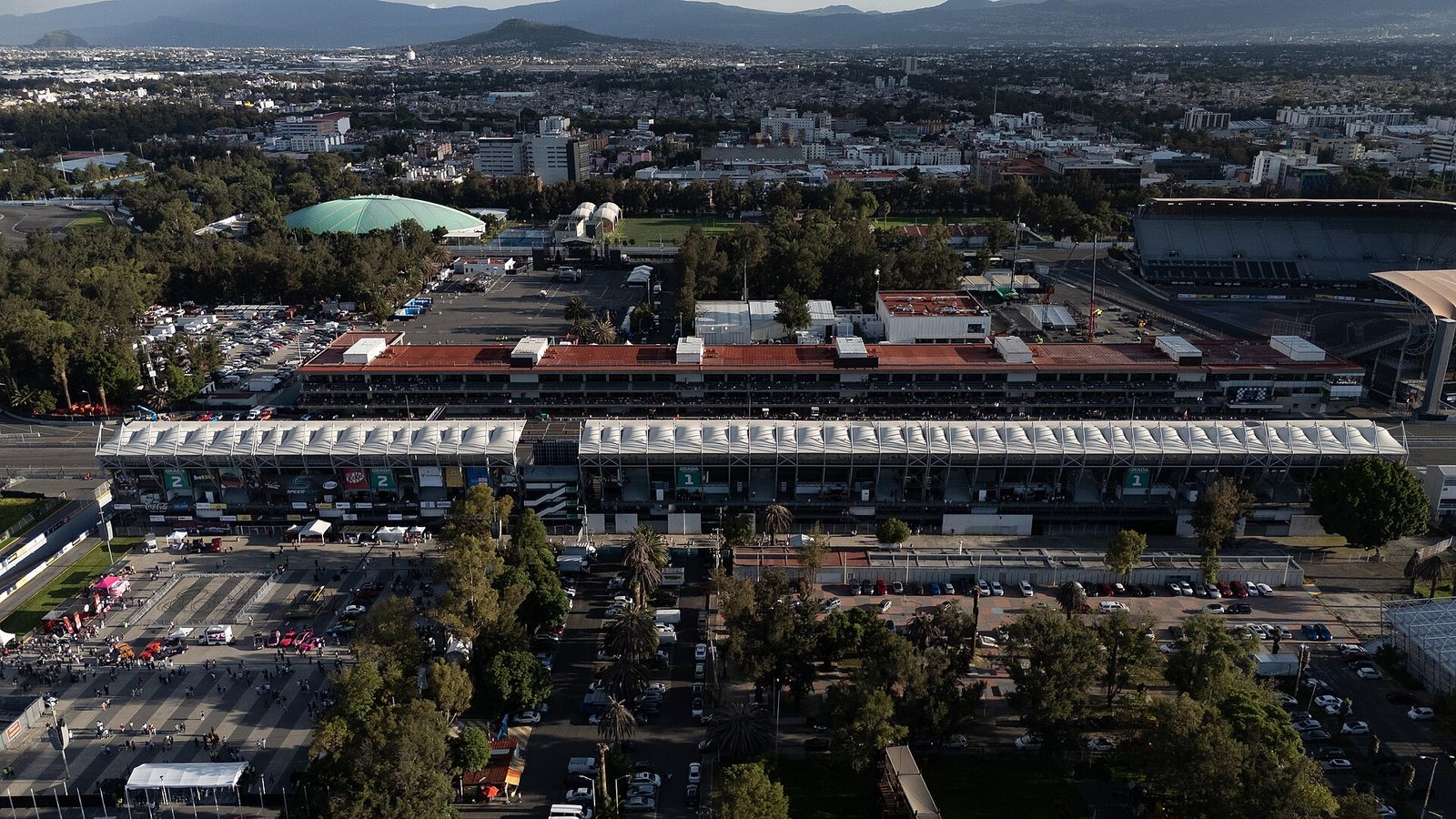 Aerial view of large racetrack grandstand, paddock and surrounding city