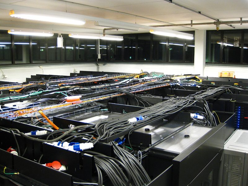 server room with racks, cables laid across tops, fluorescent lights