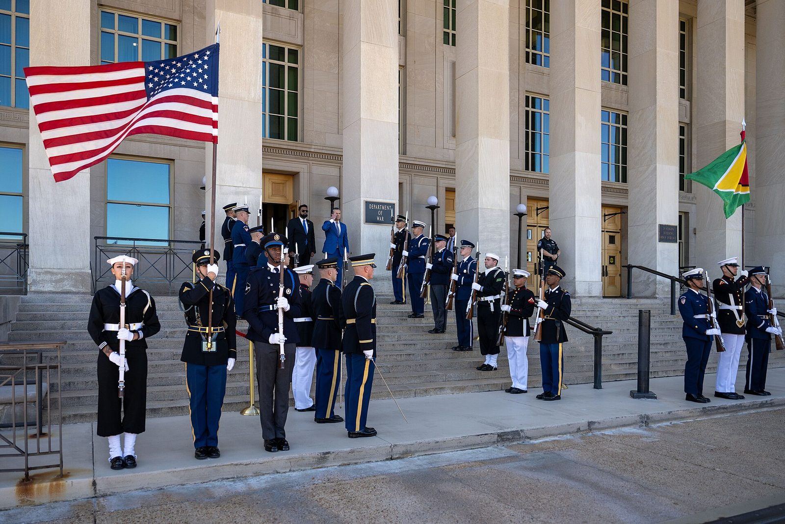Honour guard lined on steps outside entrance, two men standing by doorway
