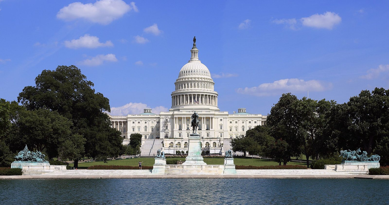 Large white domed government building with statue and reflecting pool