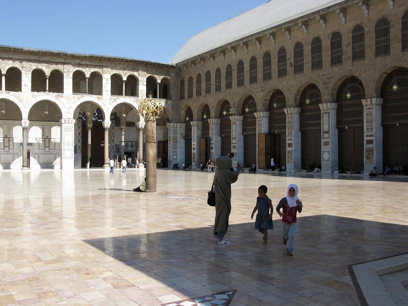 spacious mosque courtyard, columns, adult and children walking, Damascus