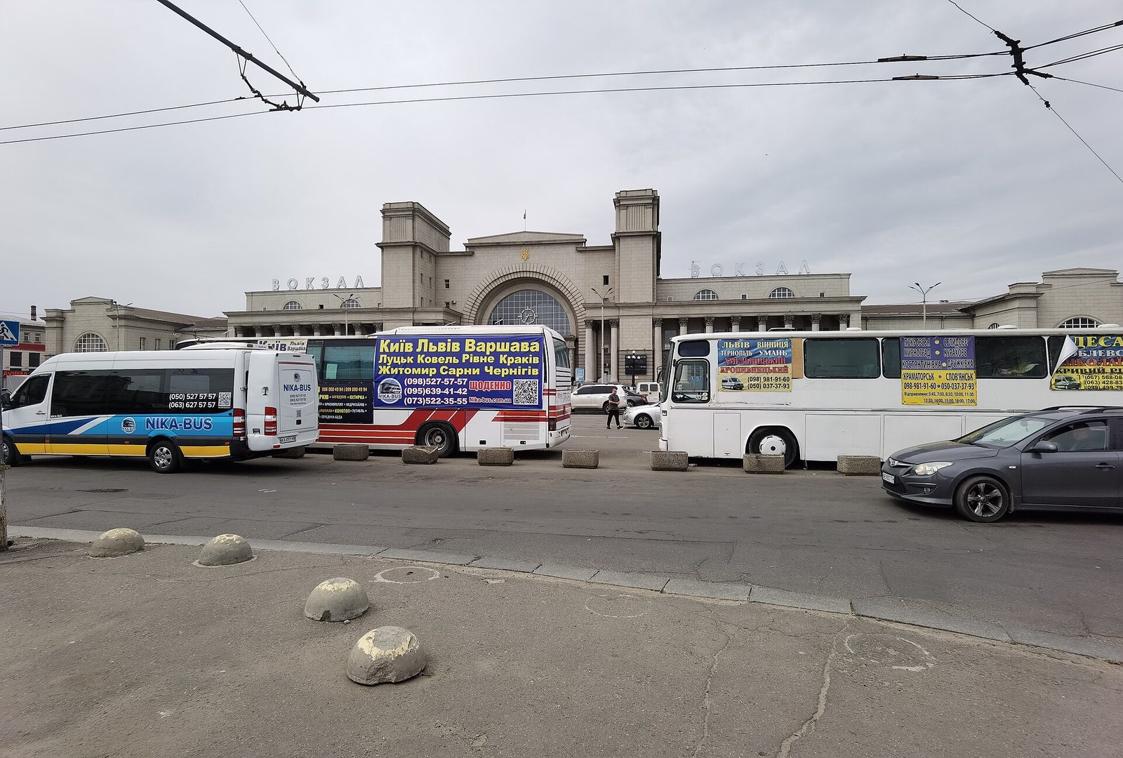 Front of station building, several parked long-distance buses, cloudy sky, Dnipro railway station