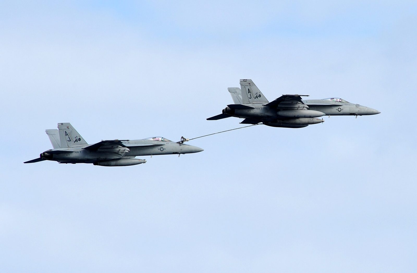 Two fighter jets in mid-air, one refuelling from the other