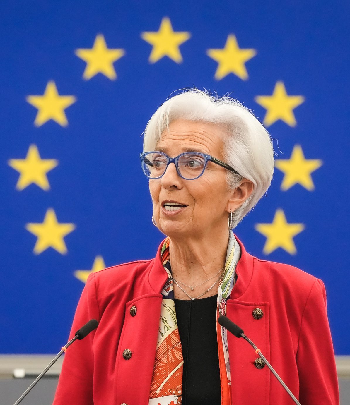 Woman speaking at a podium, EU flag stars behind
