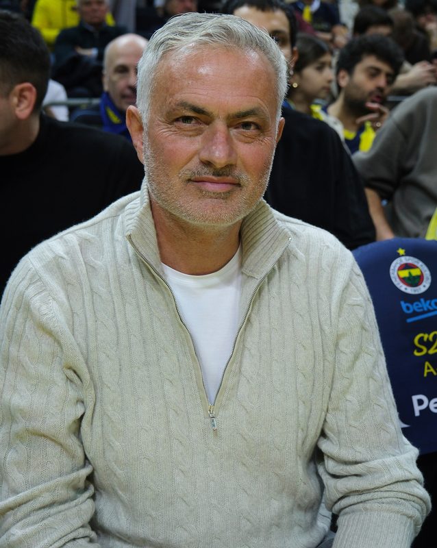 Close portrait of a man smiling, crowd visible behind him