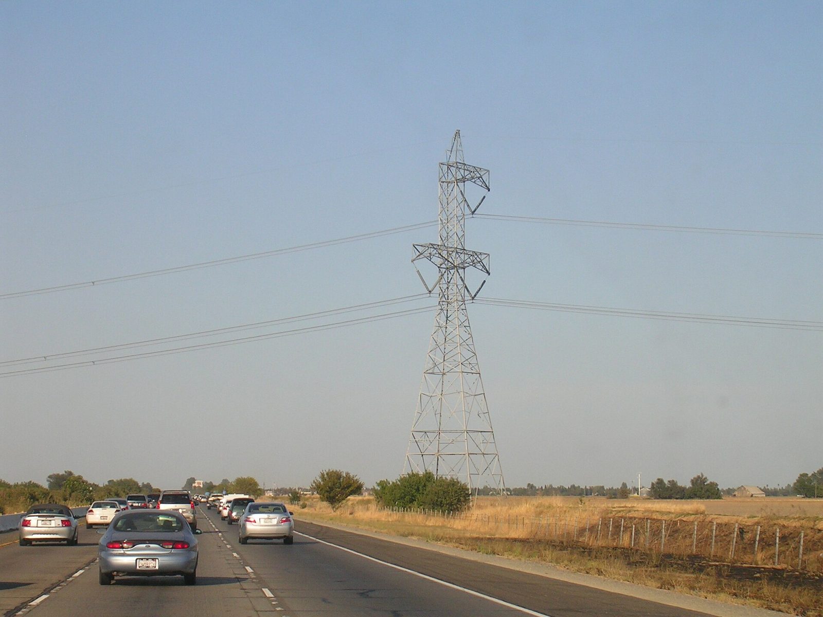multi-lane highway with cars, tall transmission tower at roadside, Vacaville