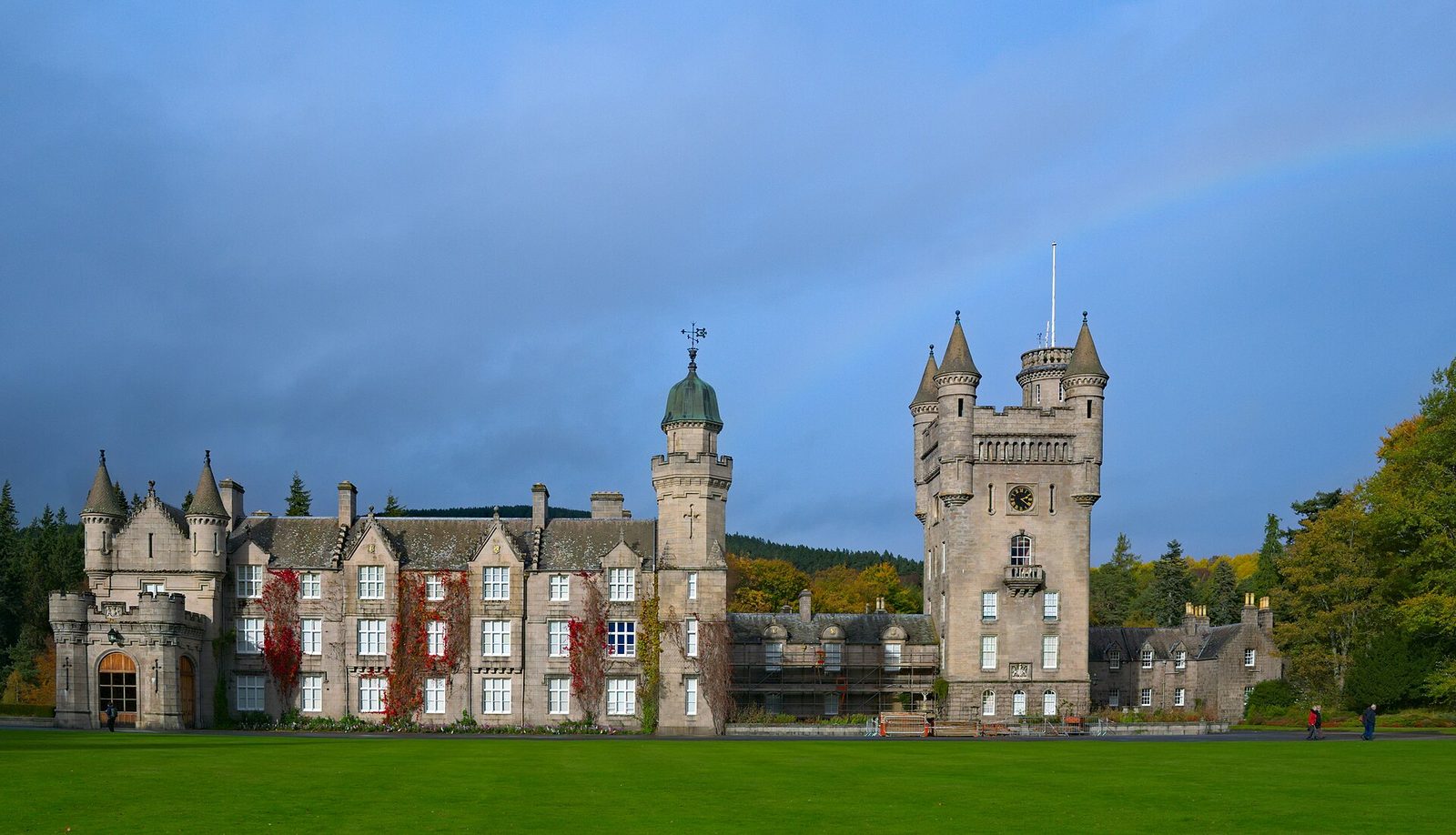 Wide view of castle, large lawn, trees, faint rainbow above building, Balmoral Castle