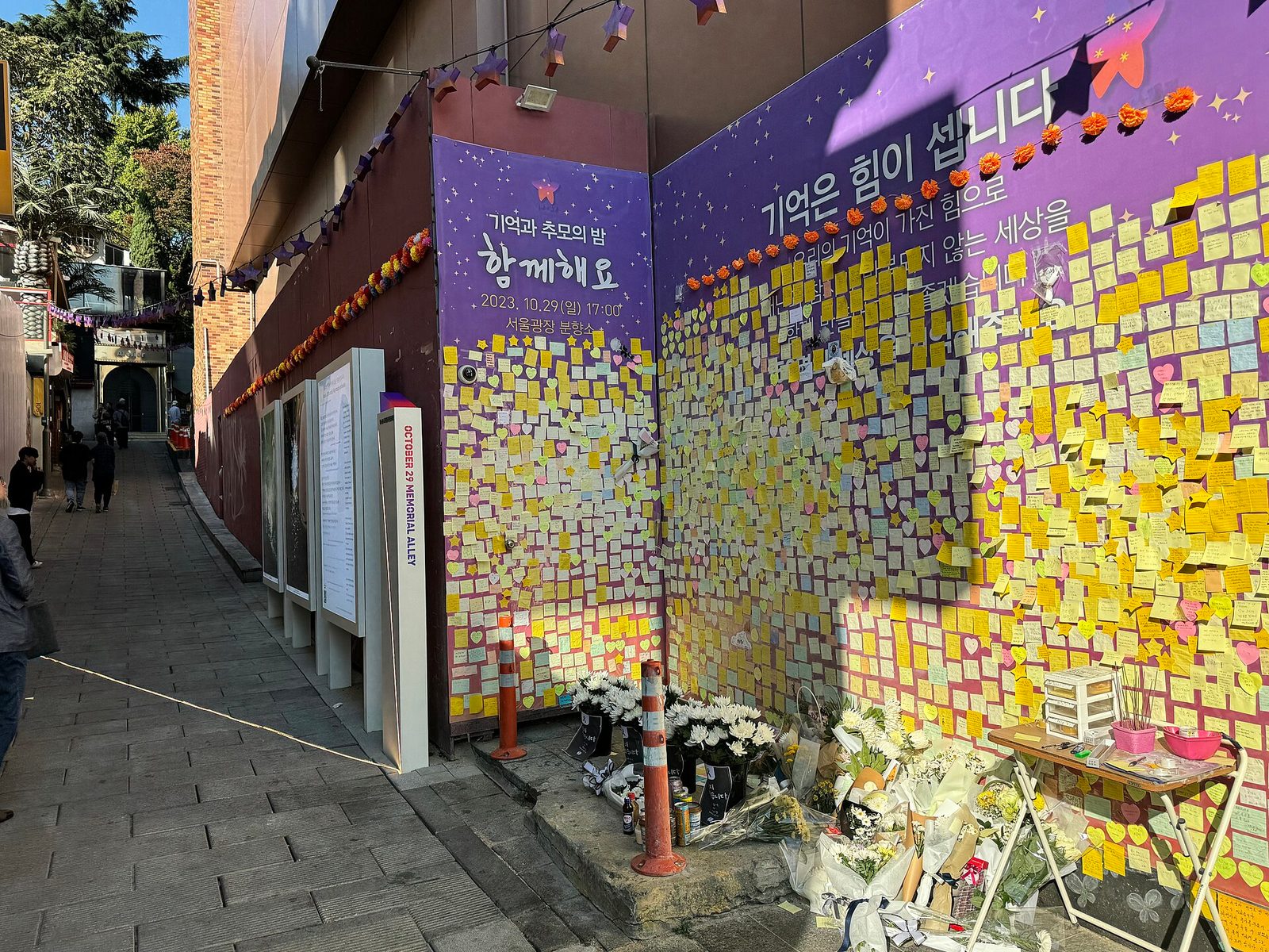 wall covered in hundreds of sticky notes, flowers and small memorial items, Itaewon