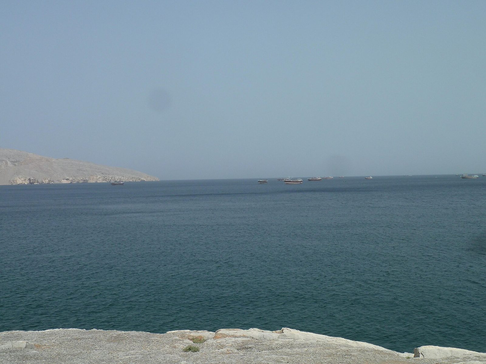 Seascape with several small boats off a rocky coastline, Khasab