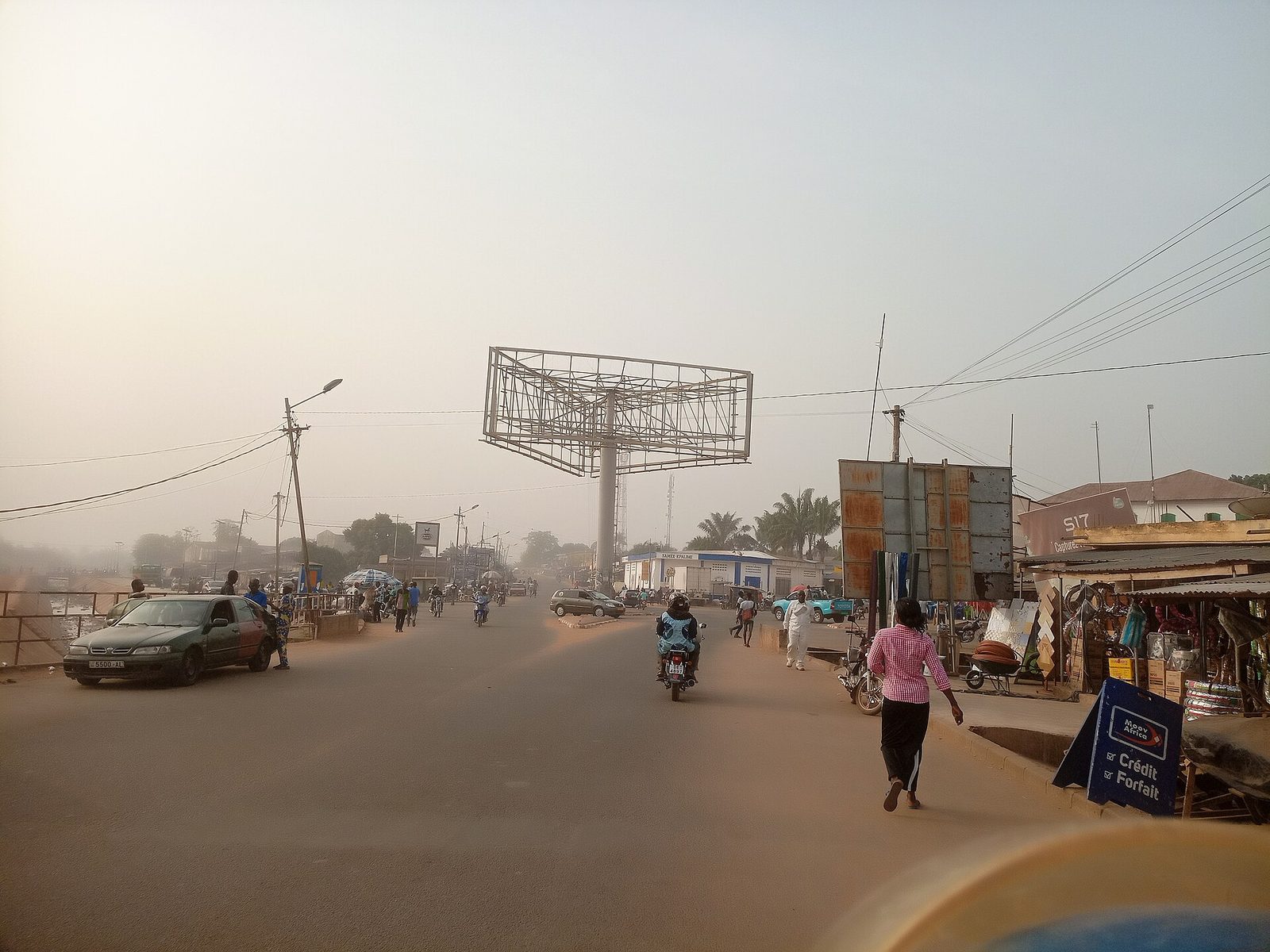 broad town street with traffic, large empty billboard structure, Kpalimé