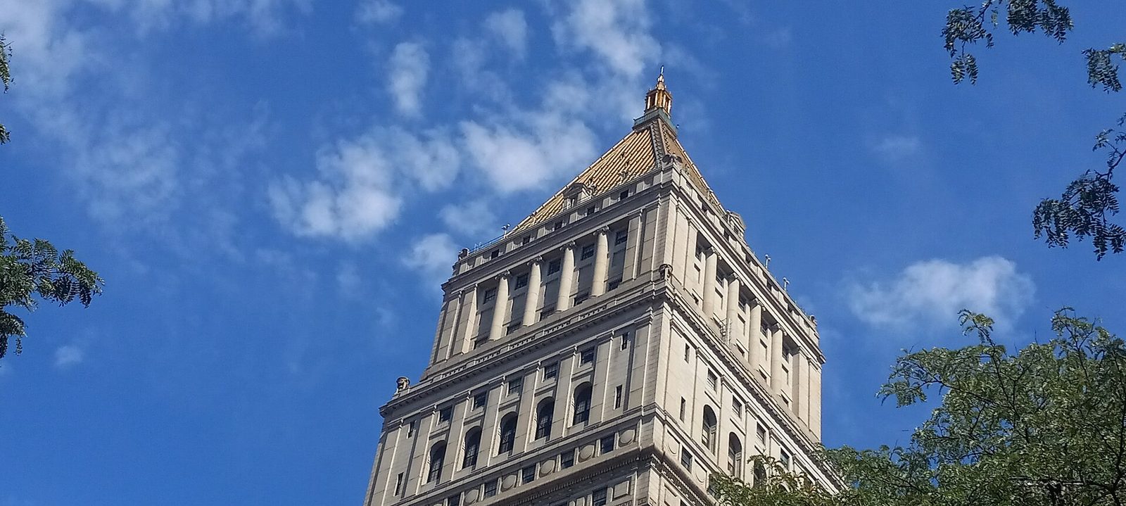 ornate stone tower of a large civic building against a blue sky, Manhattan