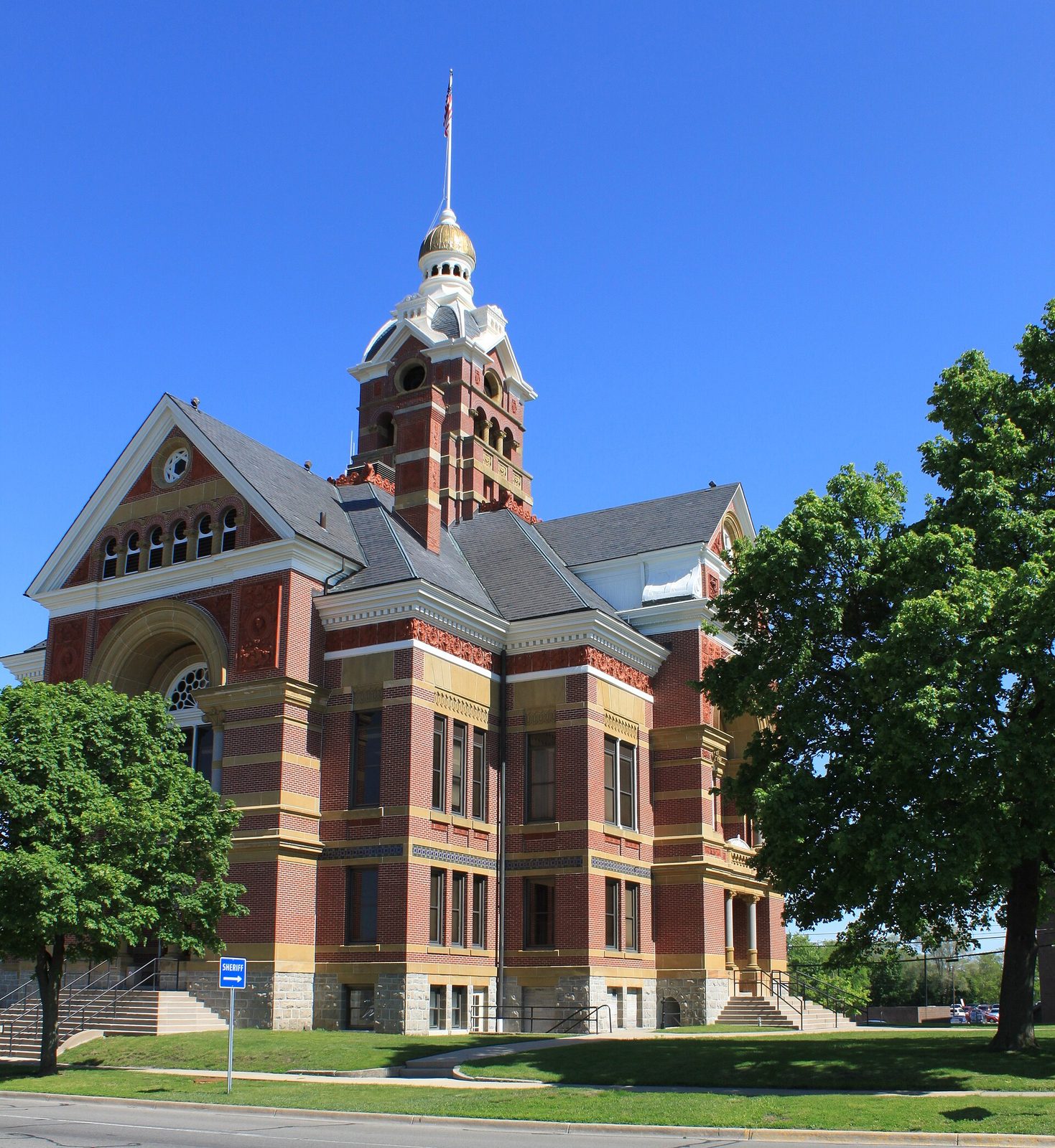 Red-brick courthouse building with tower, trees and flagpole