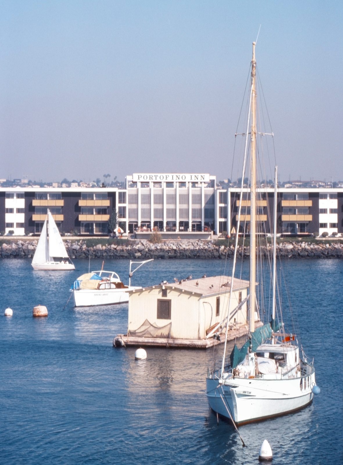 Sailboats moored in a marina, hotel building across water, King Harbor