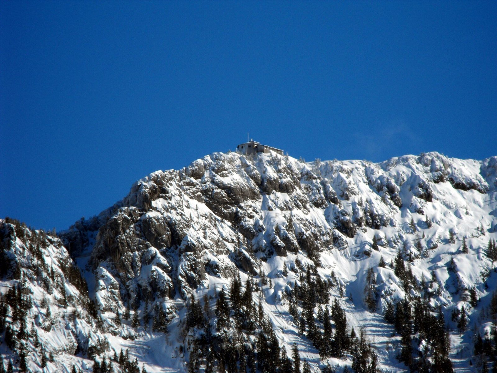 Kehlsteinhaus perched on snowy rocky ridge, clear blue sky, Kehlsteinhaus