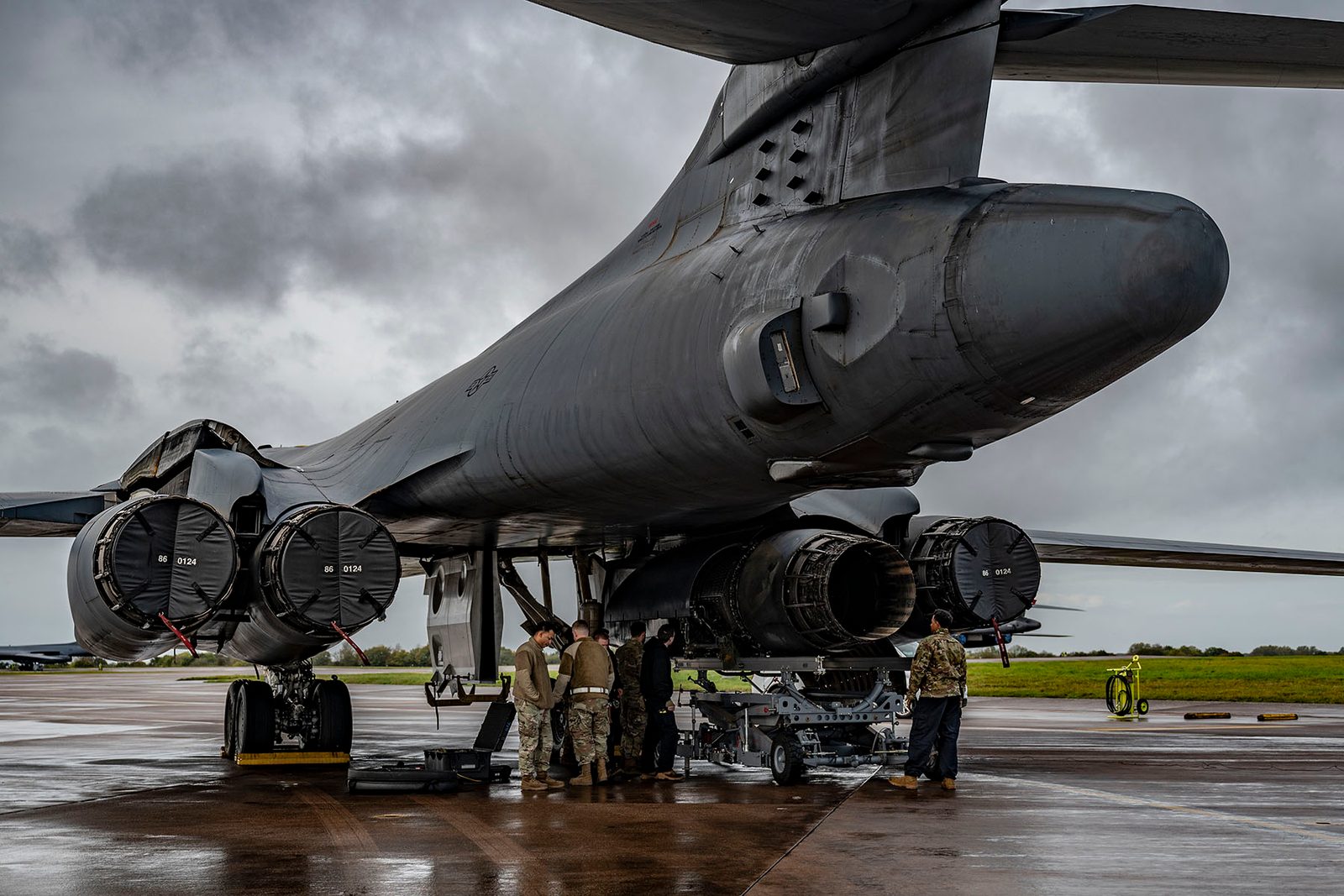Maintenance crew working under large bomber on wet tarmac, RAF Fairford