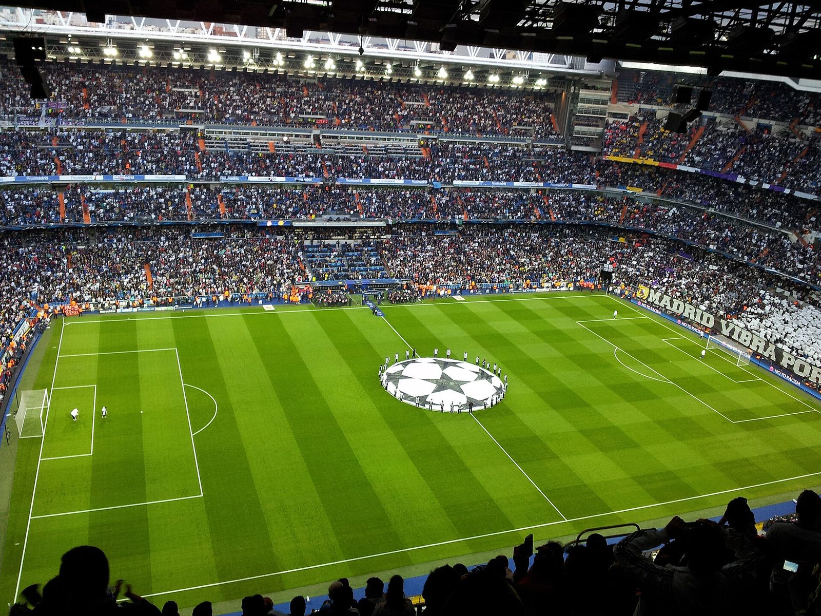 Full stadium interior with packed stands and pitch, Champions League emblem visible, Santiago Bernabéu Stadium