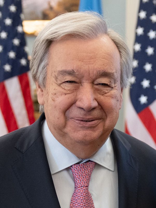 Close-up of man in suit with American flags in the background.