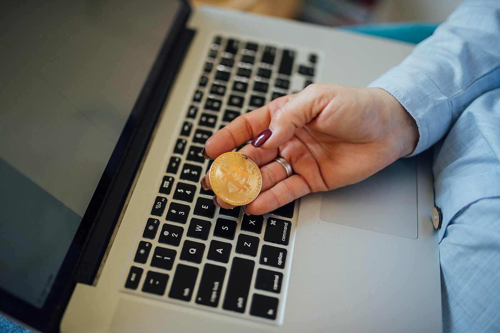 close-up of a Bitcoin coin in a hand on a laptop keyboard
