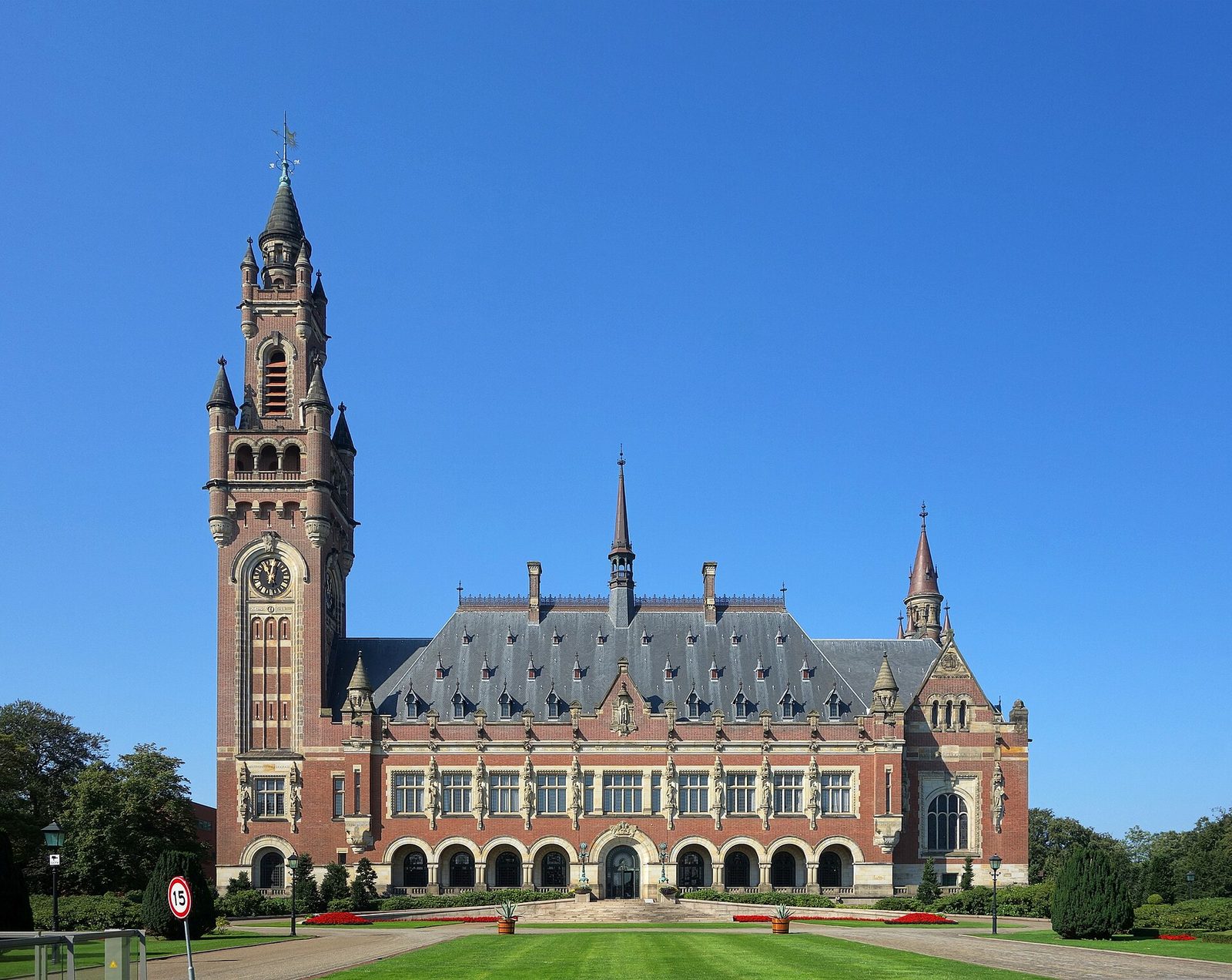 ornate red-brick palace with tall clock tower and trimmed lawn, The Hague