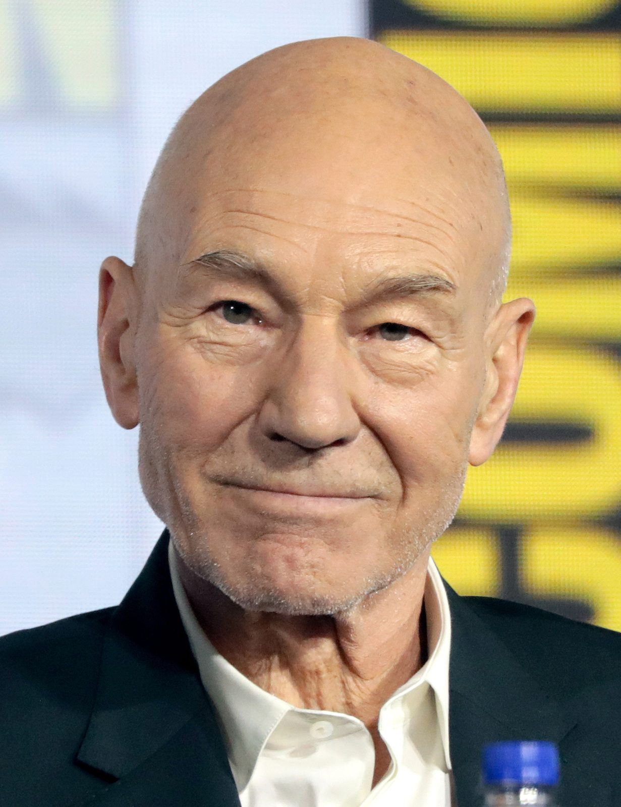 Close head-and-shoulders portrait of an older bald man, neutral background.
