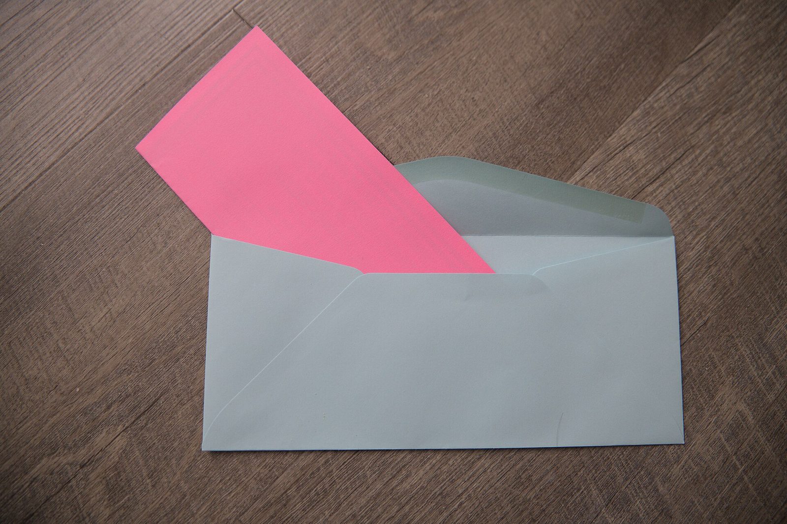 Folded pink ballot being placed into a blue mail-in envelope