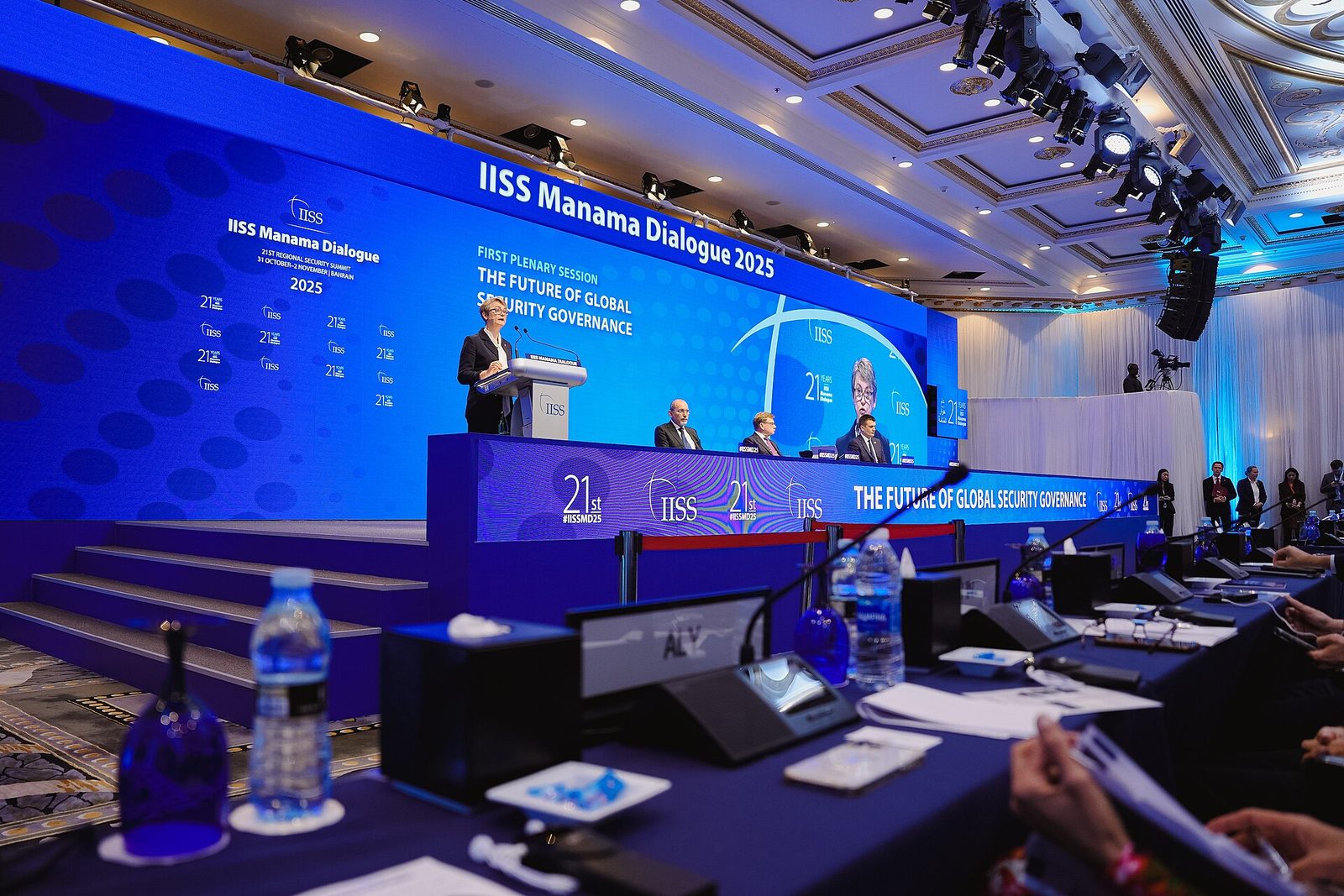 Wide view of a conference stage, large 'IISS Manama Dialogue' signage visible, Manama