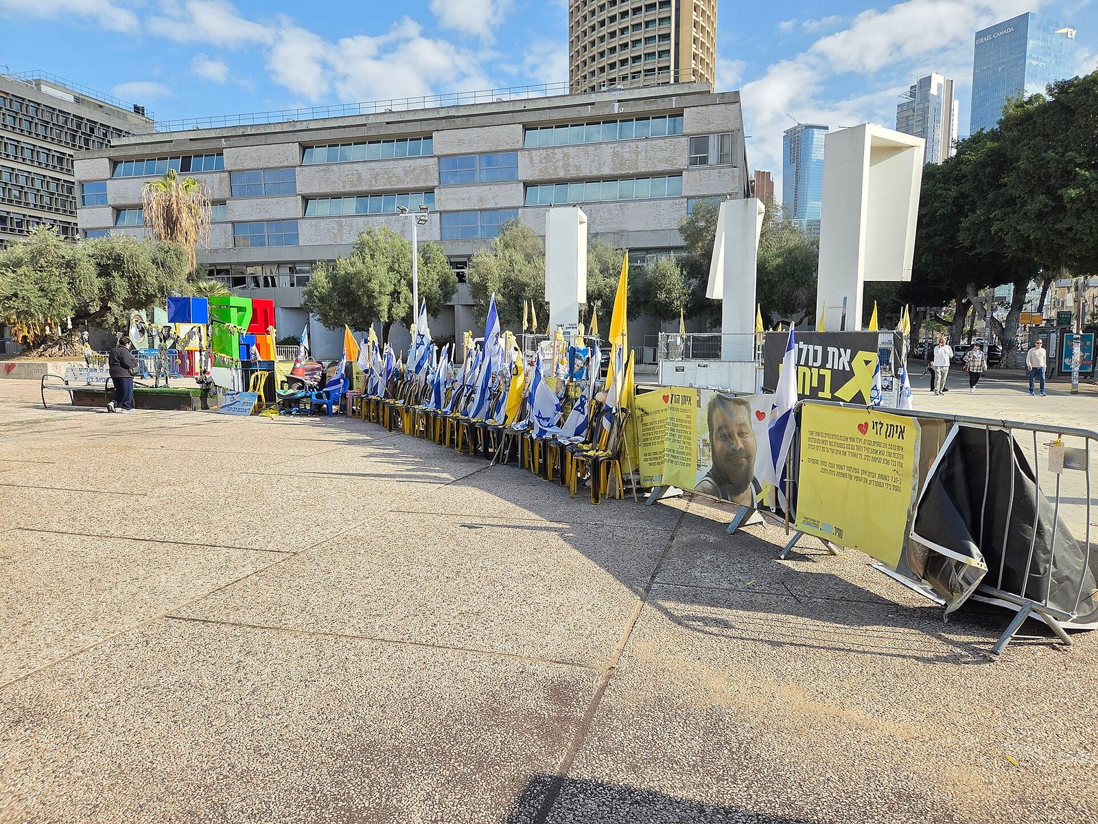 Long row of yellow chairs with flags, banners and posters in square, Hostages Square