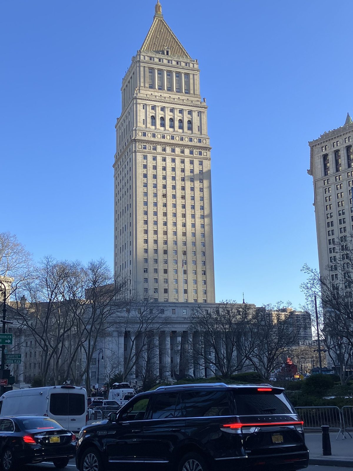 tall courthouse tower above a neoclassical columned court building and trees