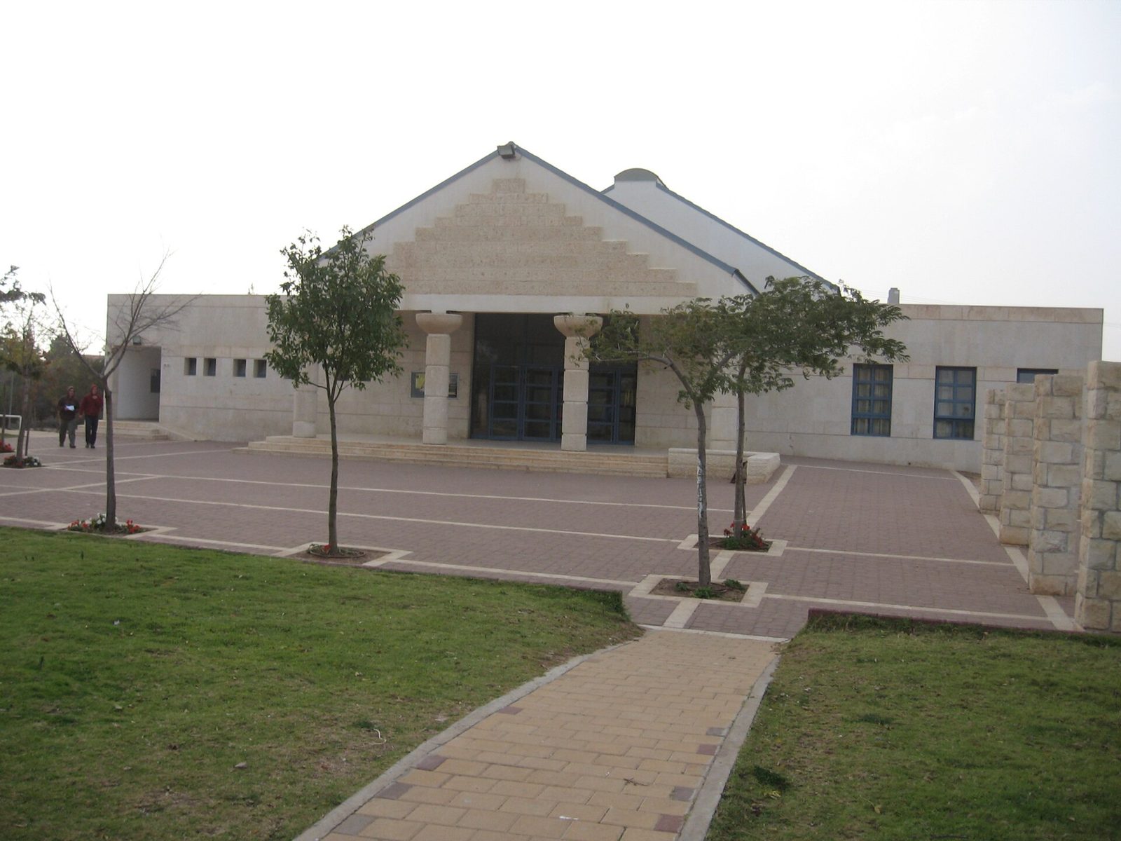 front of a modern synagogue with tiled courtyard and trees, Susya