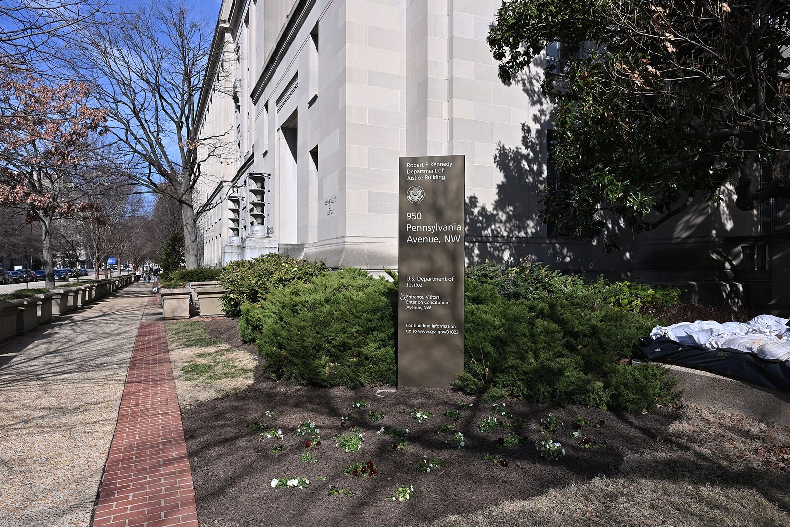 DOJ sign reading 950 Pennsylvania Avenue NW, building corner and sidewalk, Washington