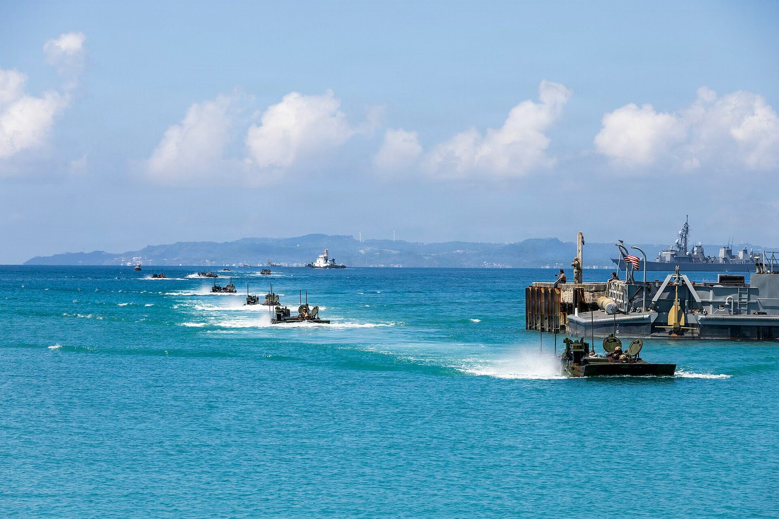 Amphibious vehicles moving from pier into turquoise coastal waters